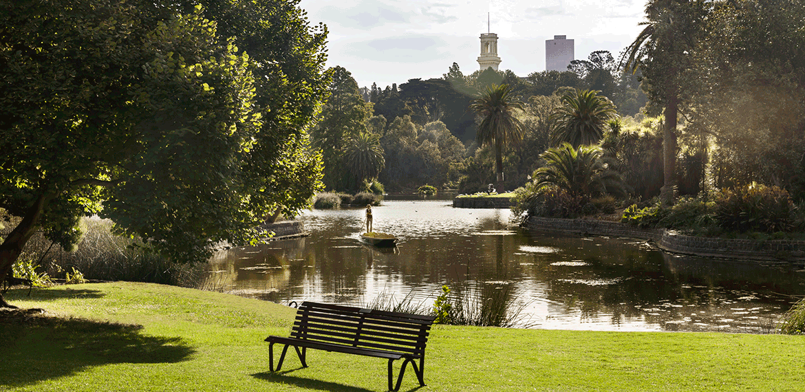 park with lake and bench in foreground and Melbourne city in background